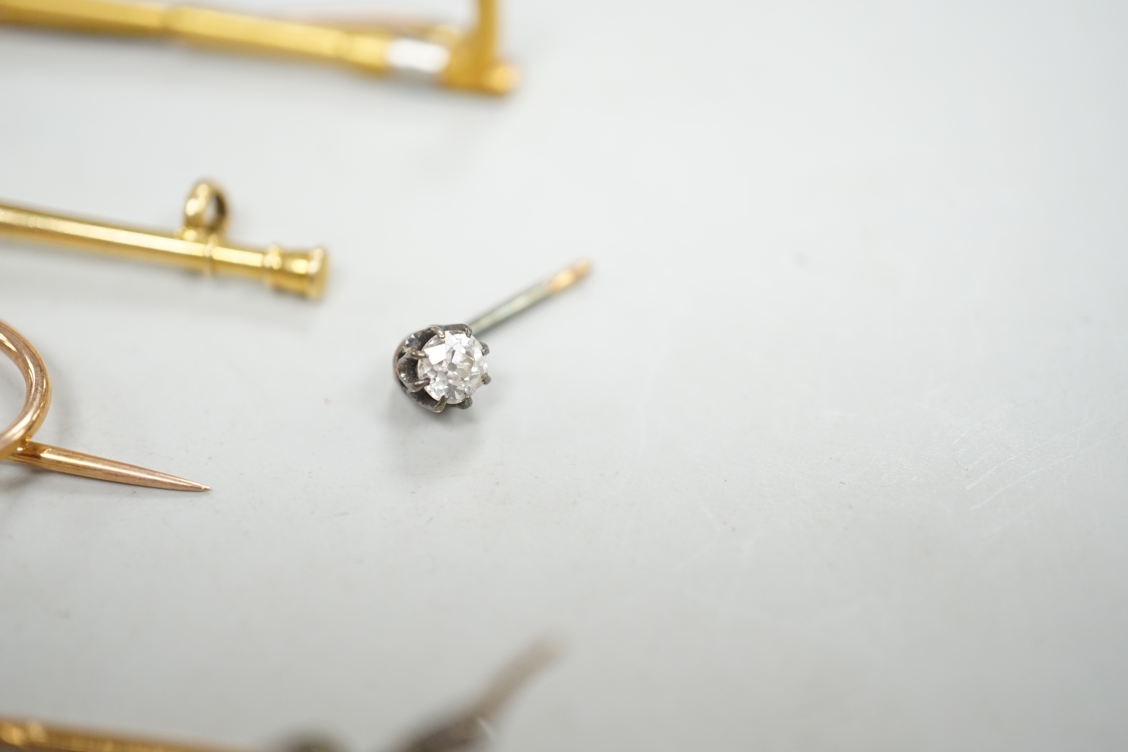 An Edwardian 15ct riding crop brooch(a.f.), 59mm, 2.8 grams, an 18ct hunting horn brooch (lacking pin) 2.1 grams, two Victorian diamond cluster set stick pins including swan in flight, a diamond set pin terminal, gross 4